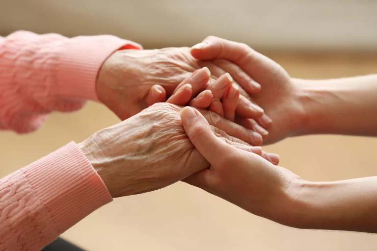 Junge Hand hält die Hand einer älteren Person – Symbol für Vertrauen und Fürsorge im Pflegedienst